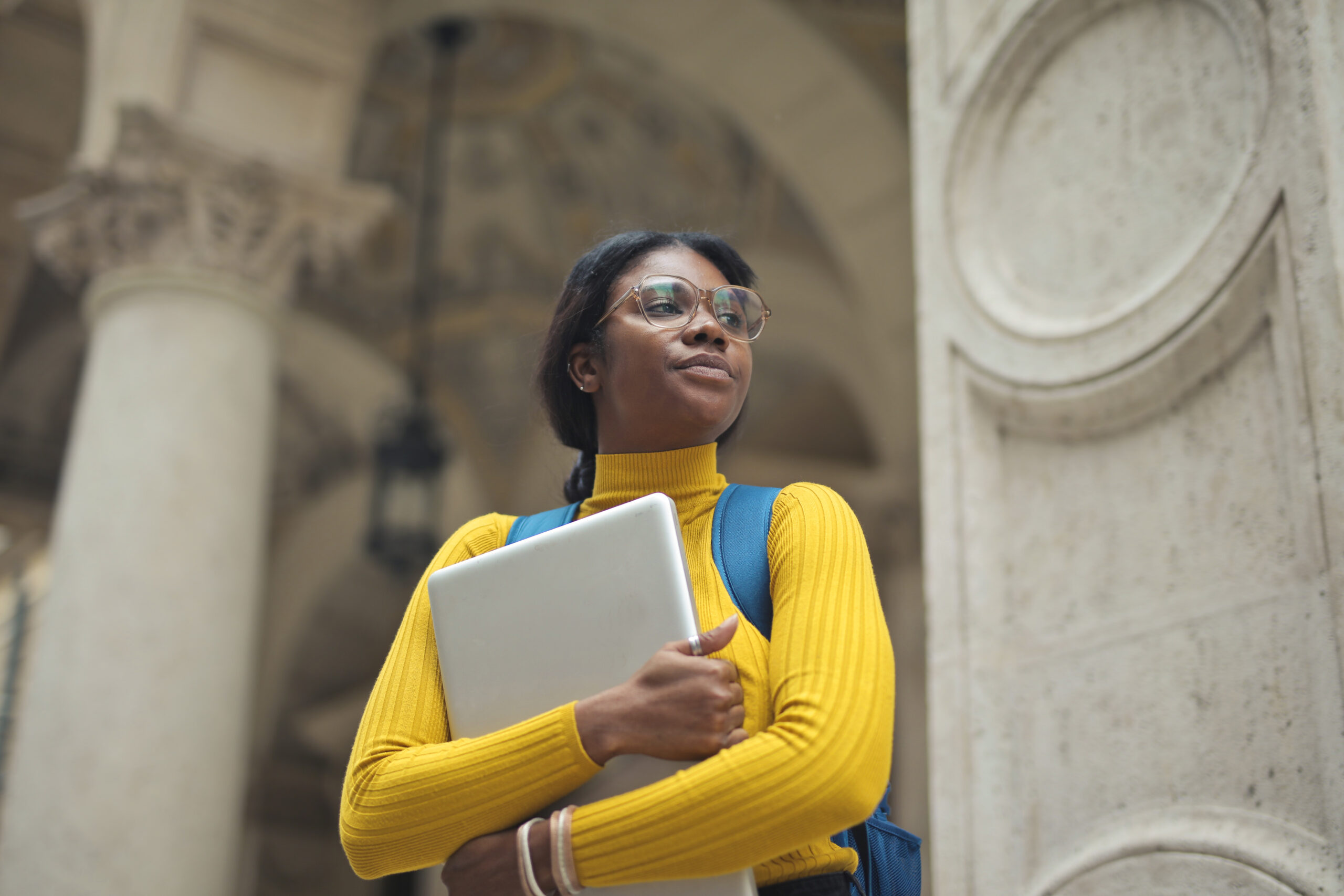 portrait of young woman with laptop in hands outside a school